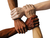 Four diverse hands and arms clasped.